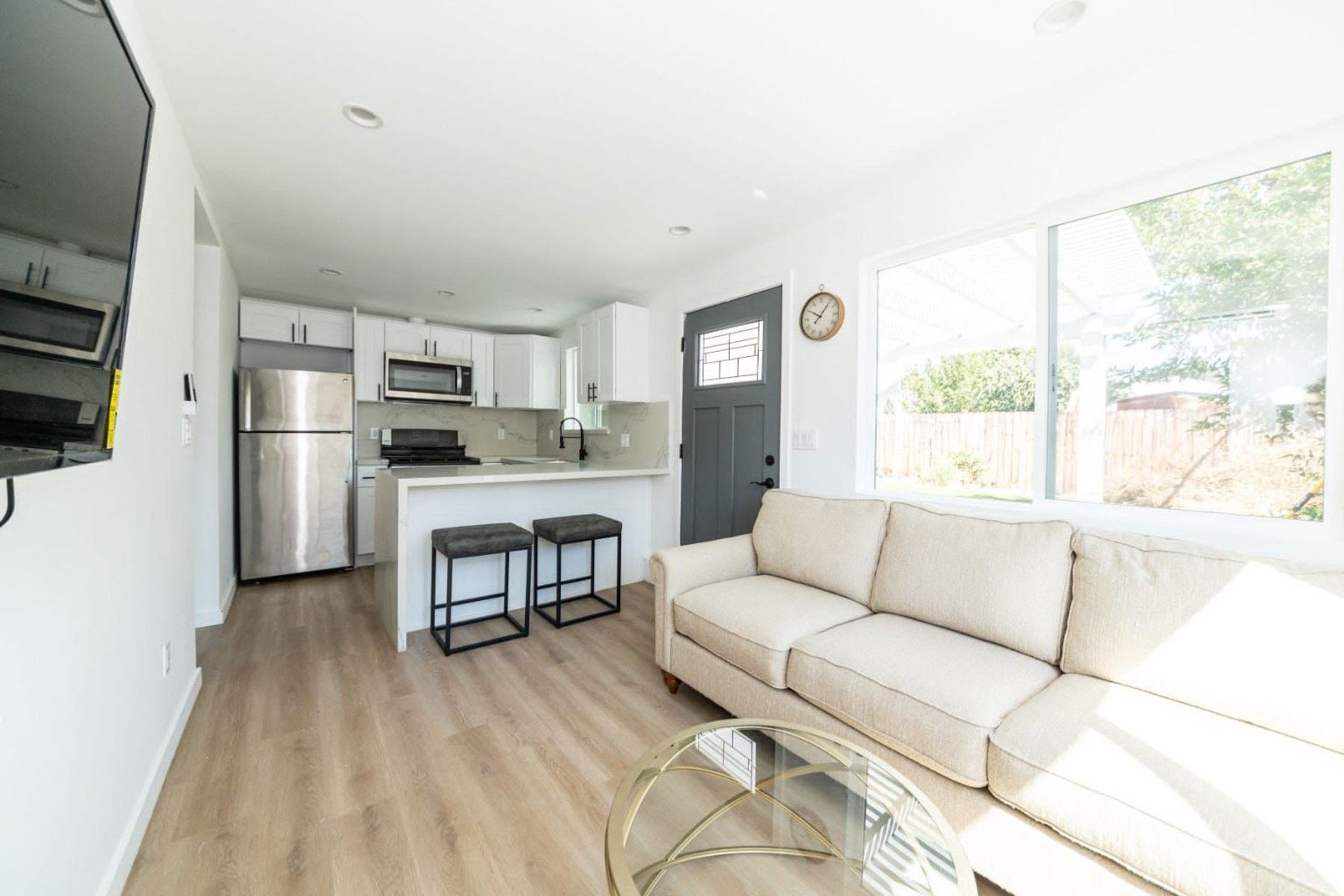 ADU interior with an open white kitchen, sitting area and light wood-look flooring