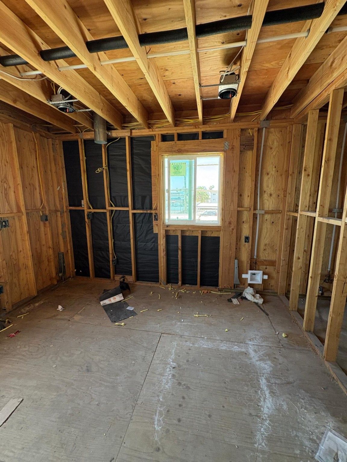 ADU room in progress showing framing, a window and rough utility work