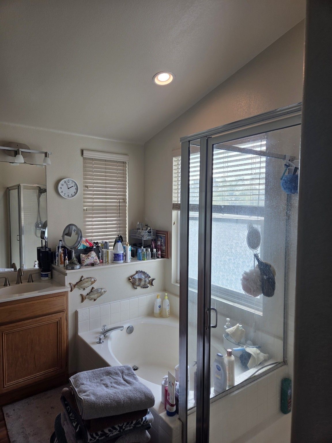 Original bathroom with wood vanity cabinets, built-in tub and framed shower enclosure.