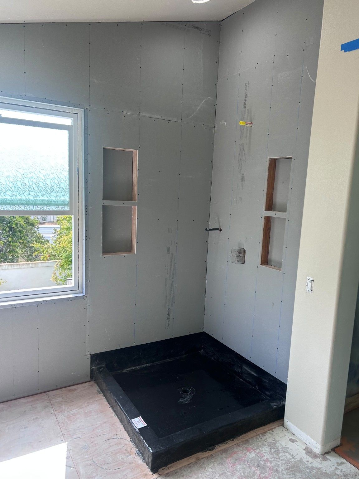 Shower wall panels with four recessed niches above the exposed shower base.
