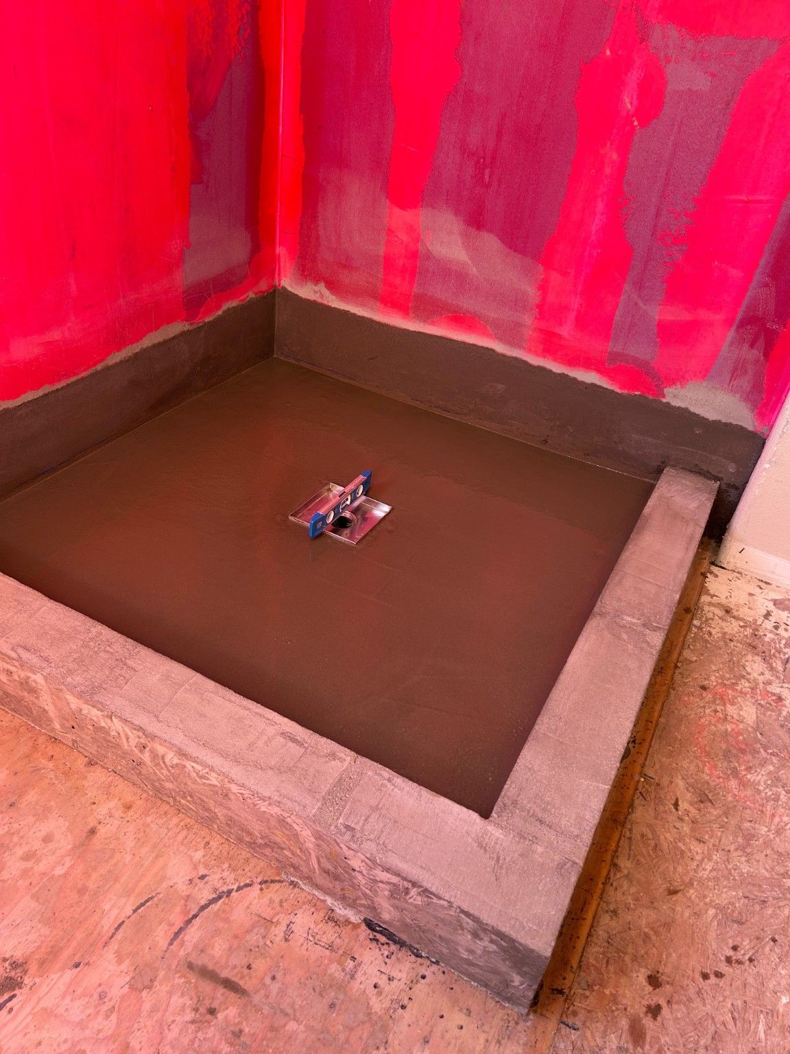 Shower floor surface and drain being worked on inside the raised curb.