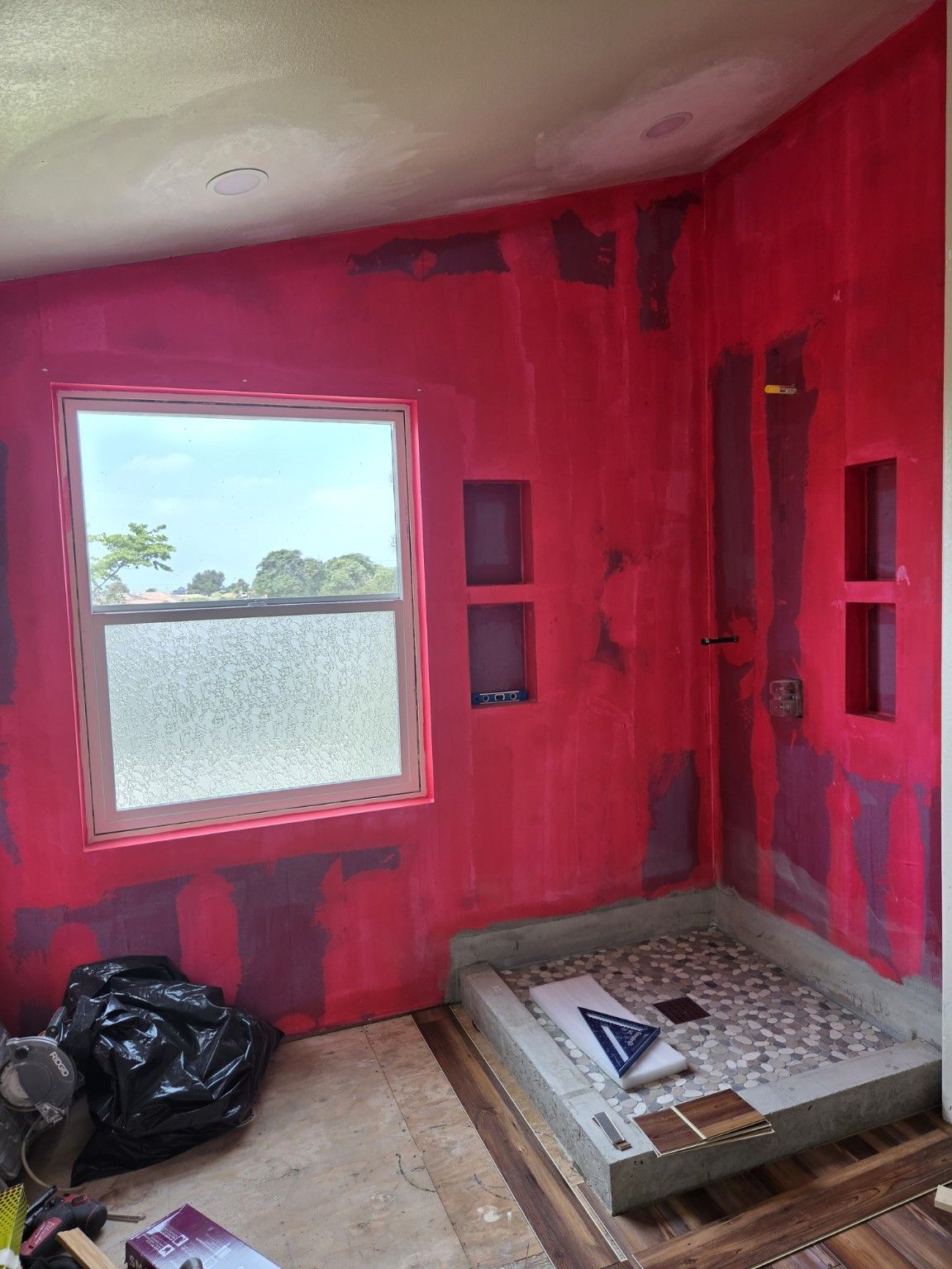 Pebble-pattern shower floor installed while surrounding walls remain in preparation.