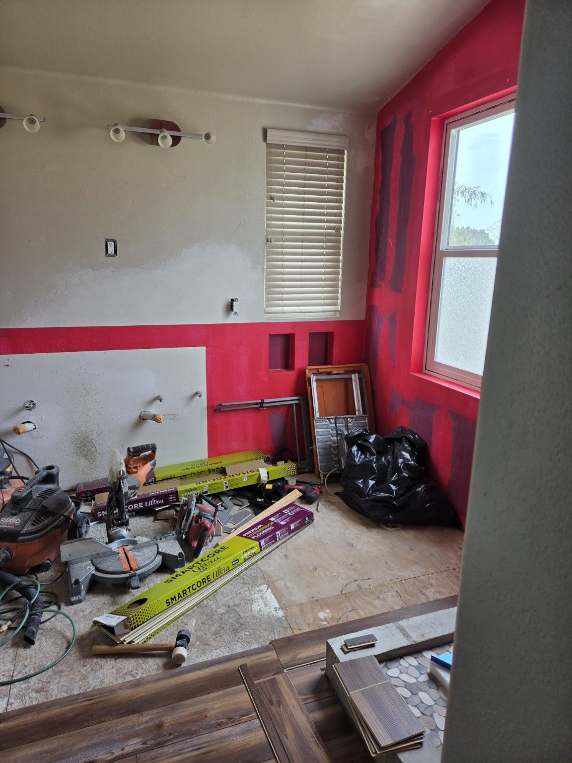 Bathroom flooring installation underway, with tools and materials beside the shower.