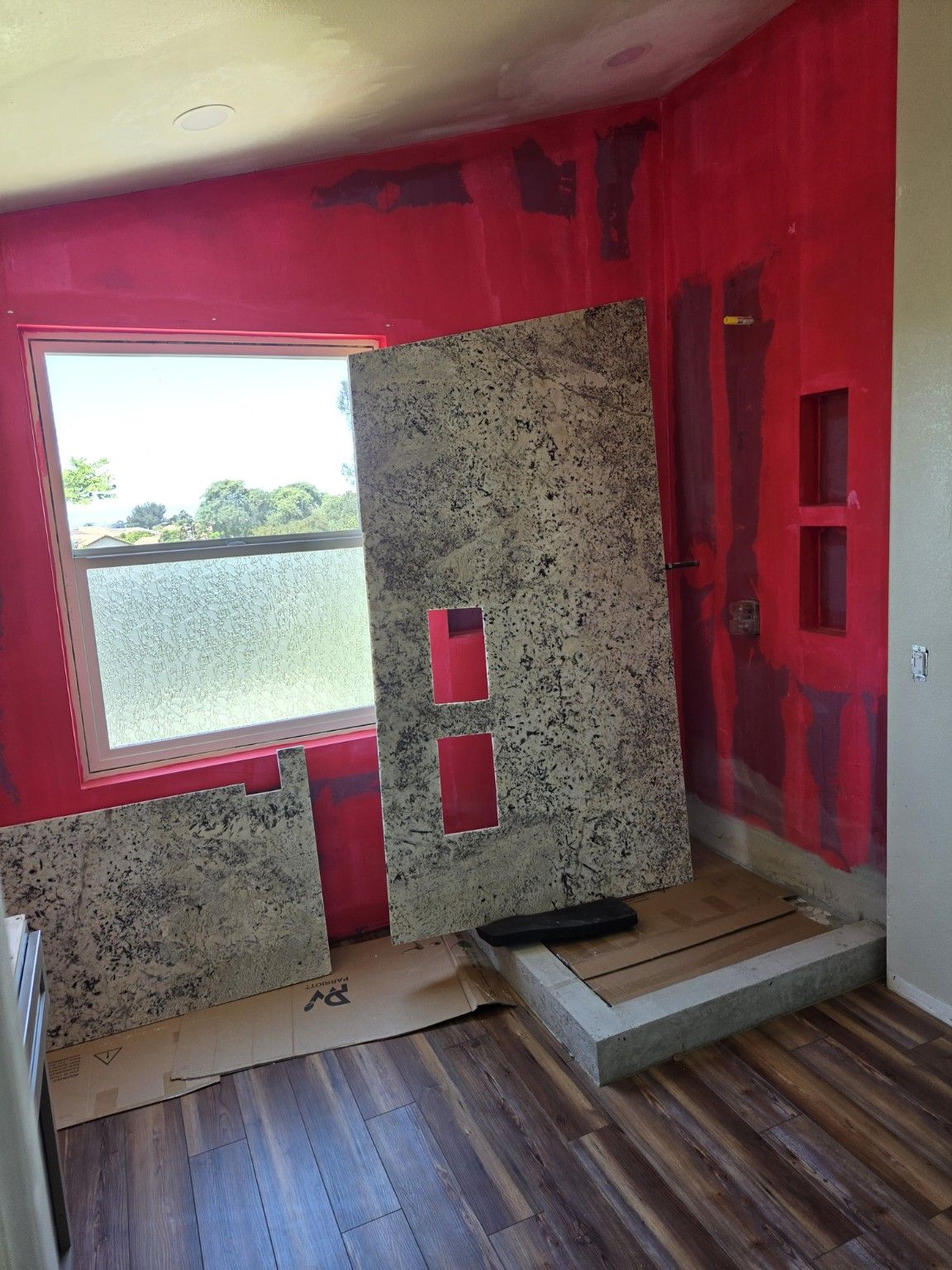 Speckled wall panels with niche cutouts ready for fitting beside the bathroom window.