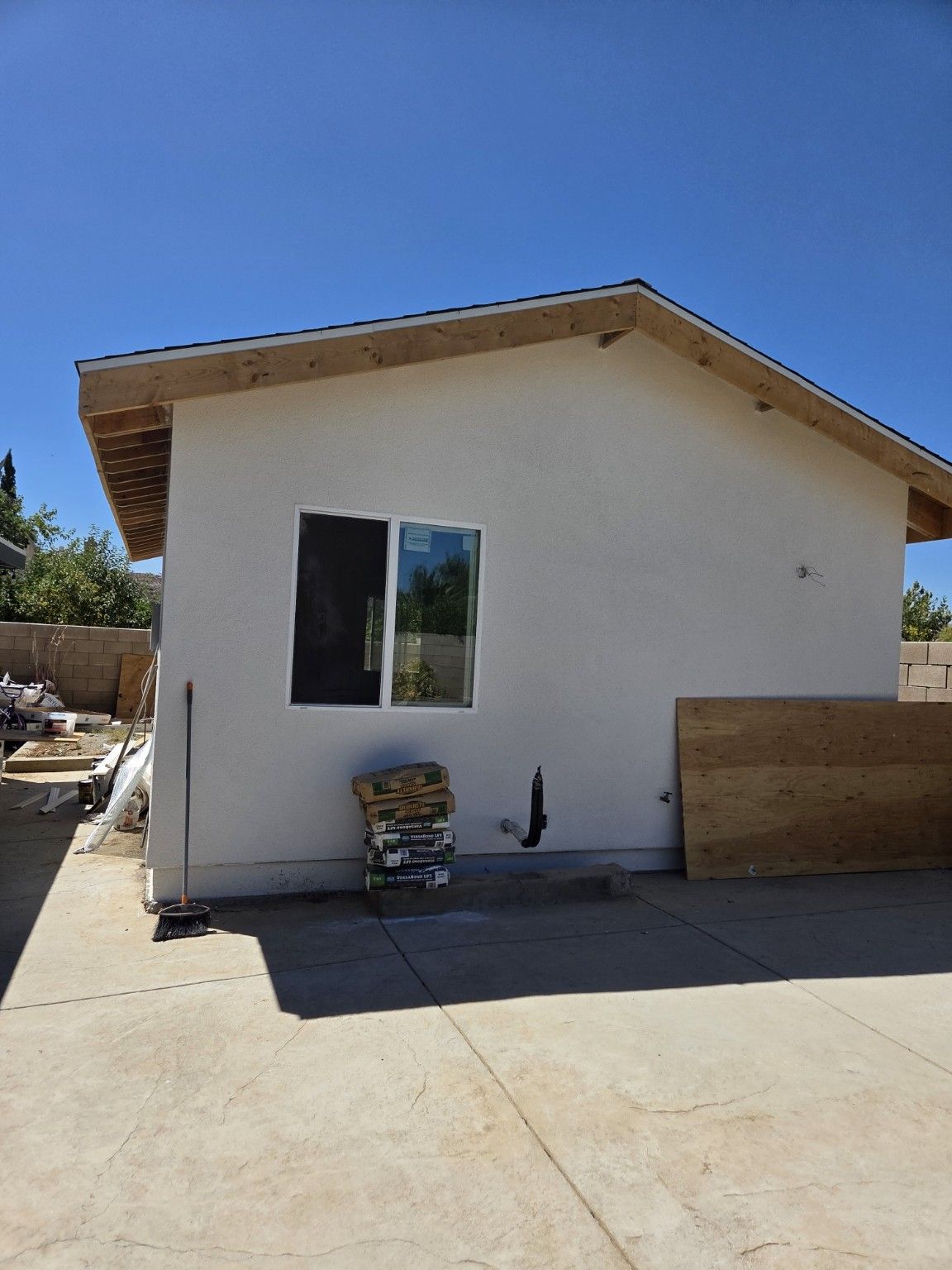 Small building exterior with a window and construction materials outside