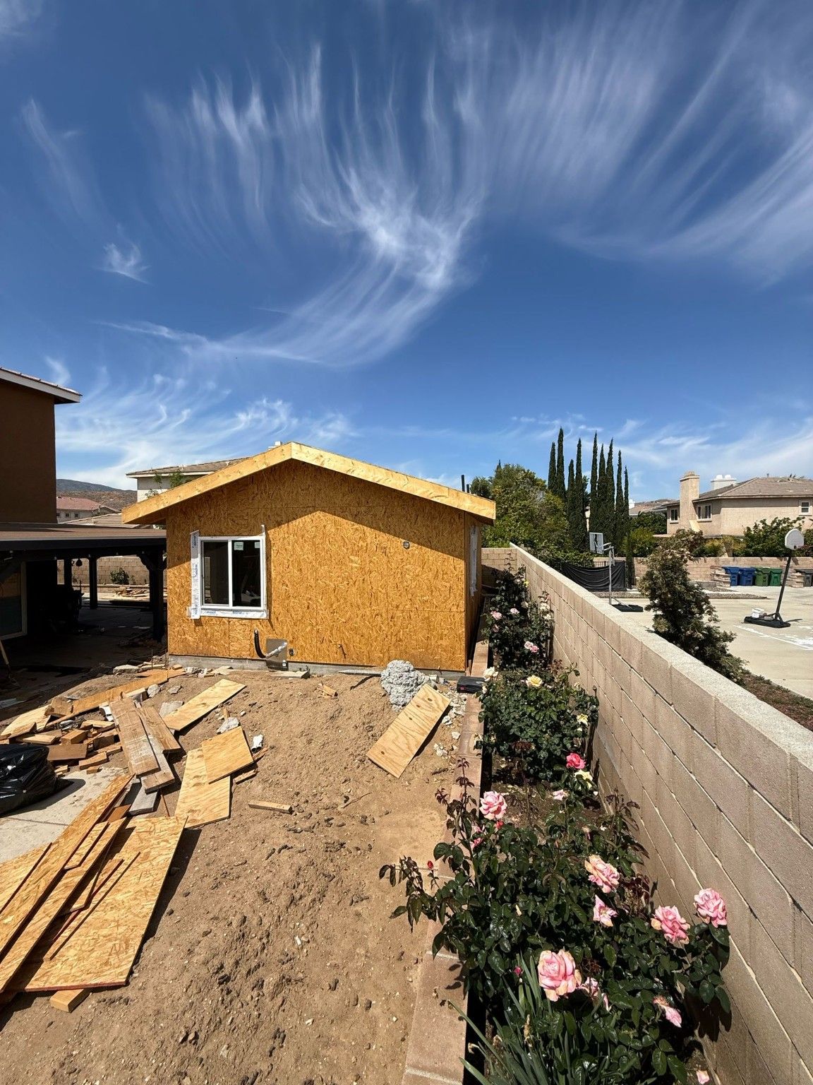 Small building with exposed exterior sheathing and construction materials nearby