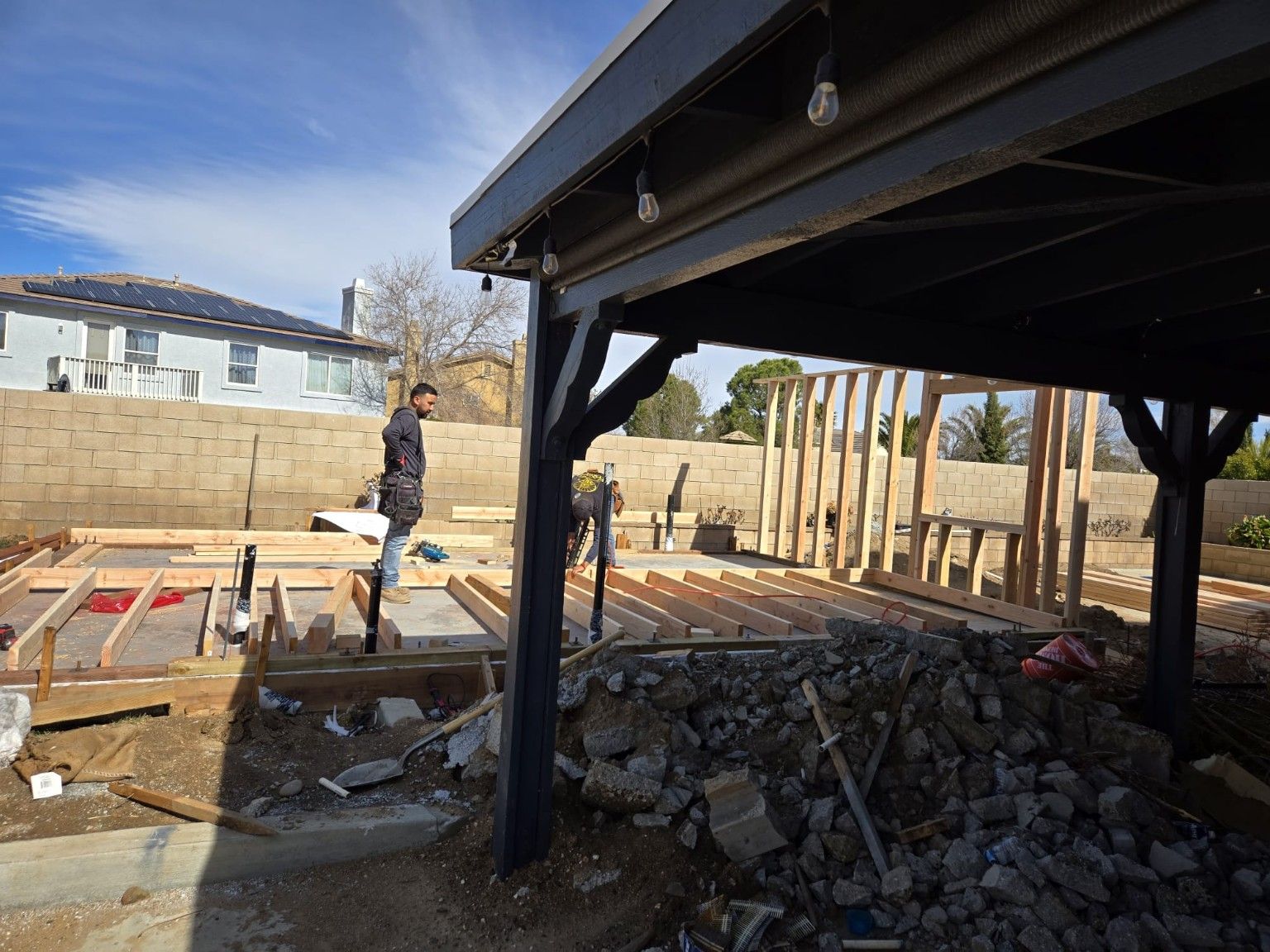 Building framing and construction materials beside an existing outdoor cover