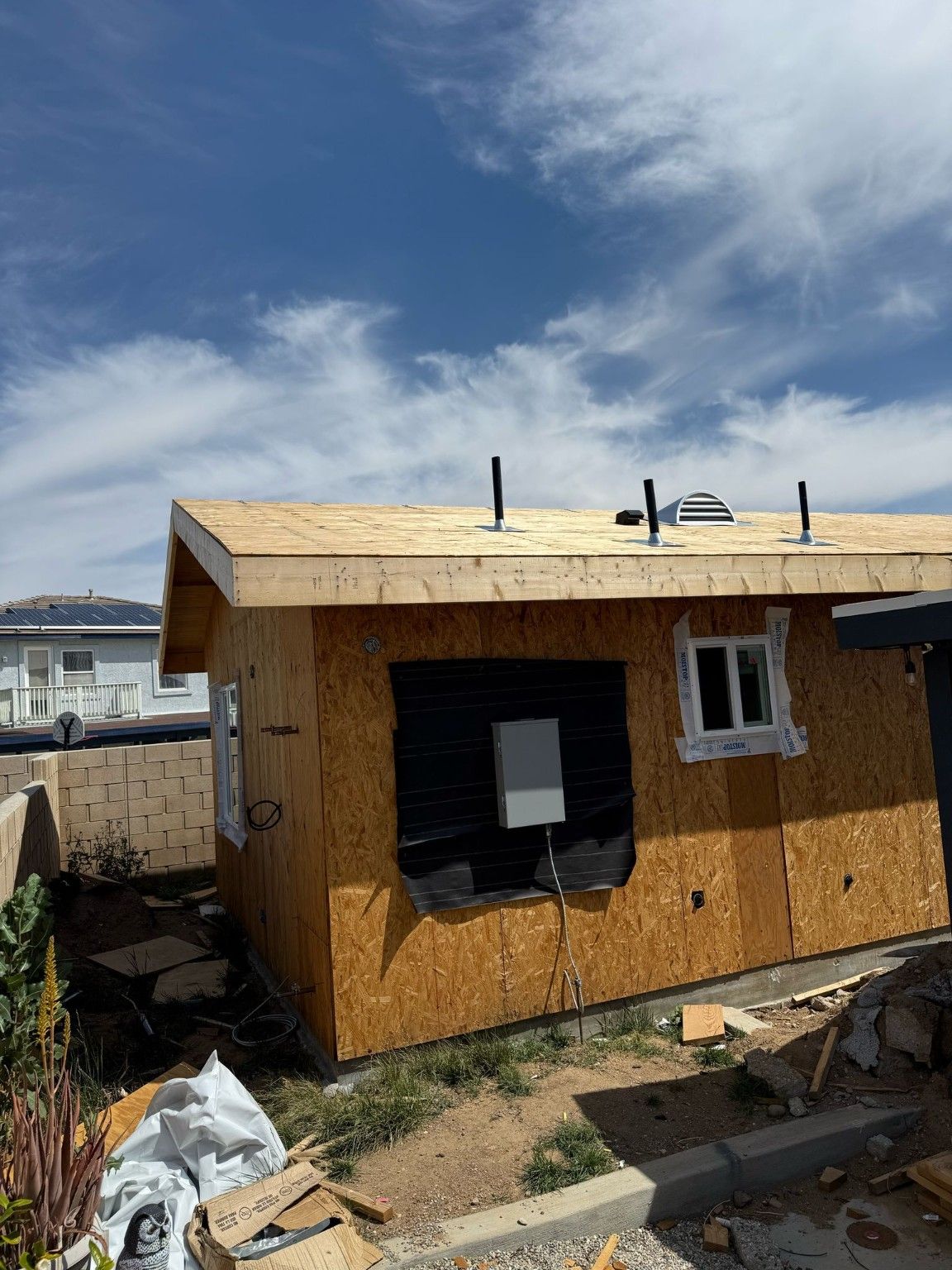 Building exterior with wall sheathing, roof framing and utility vents