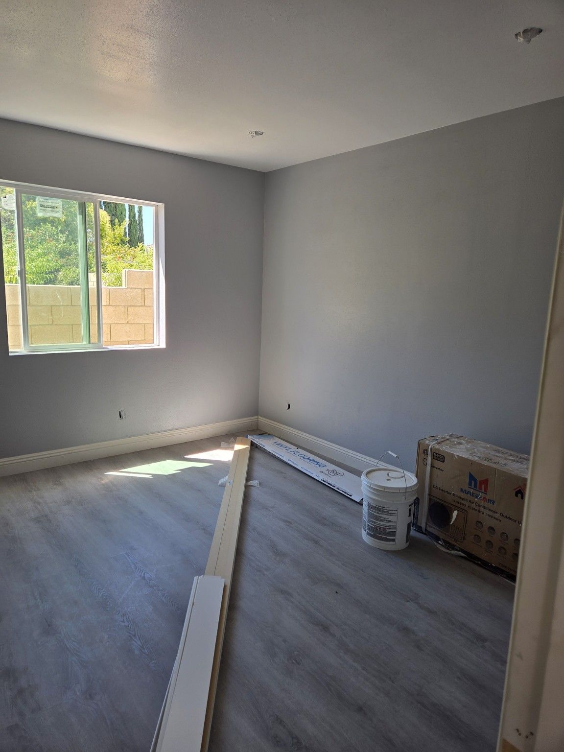 Room with light walls, new flooring and materials awaiting installation