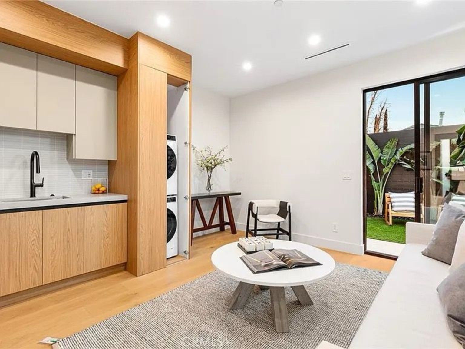 Wood kitchen cabinetry and a sitting area beside a glass door opening onto an outdoor space