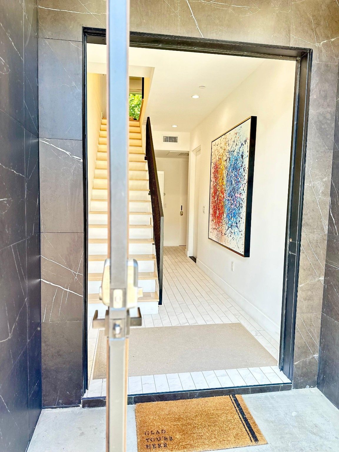 Entryway with tile flooring and a stairway beside an interior hallway