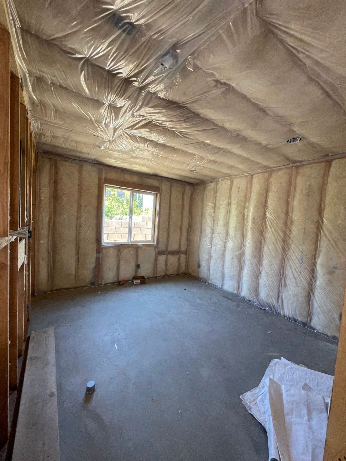Room with wall and ceiling insulation and an unfinished gray floor