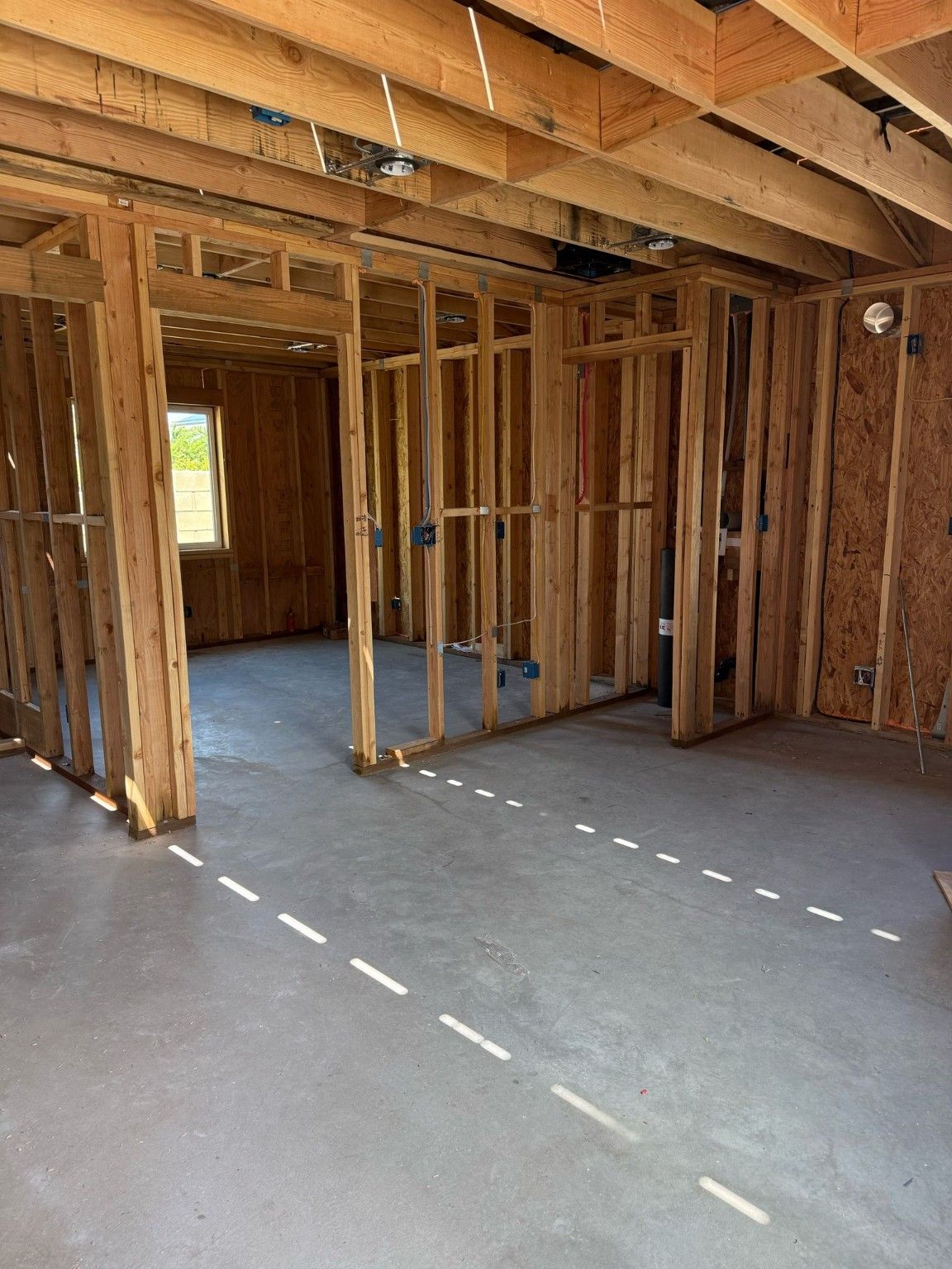 Wood wall and ceiling framing above an unfinished gray floor