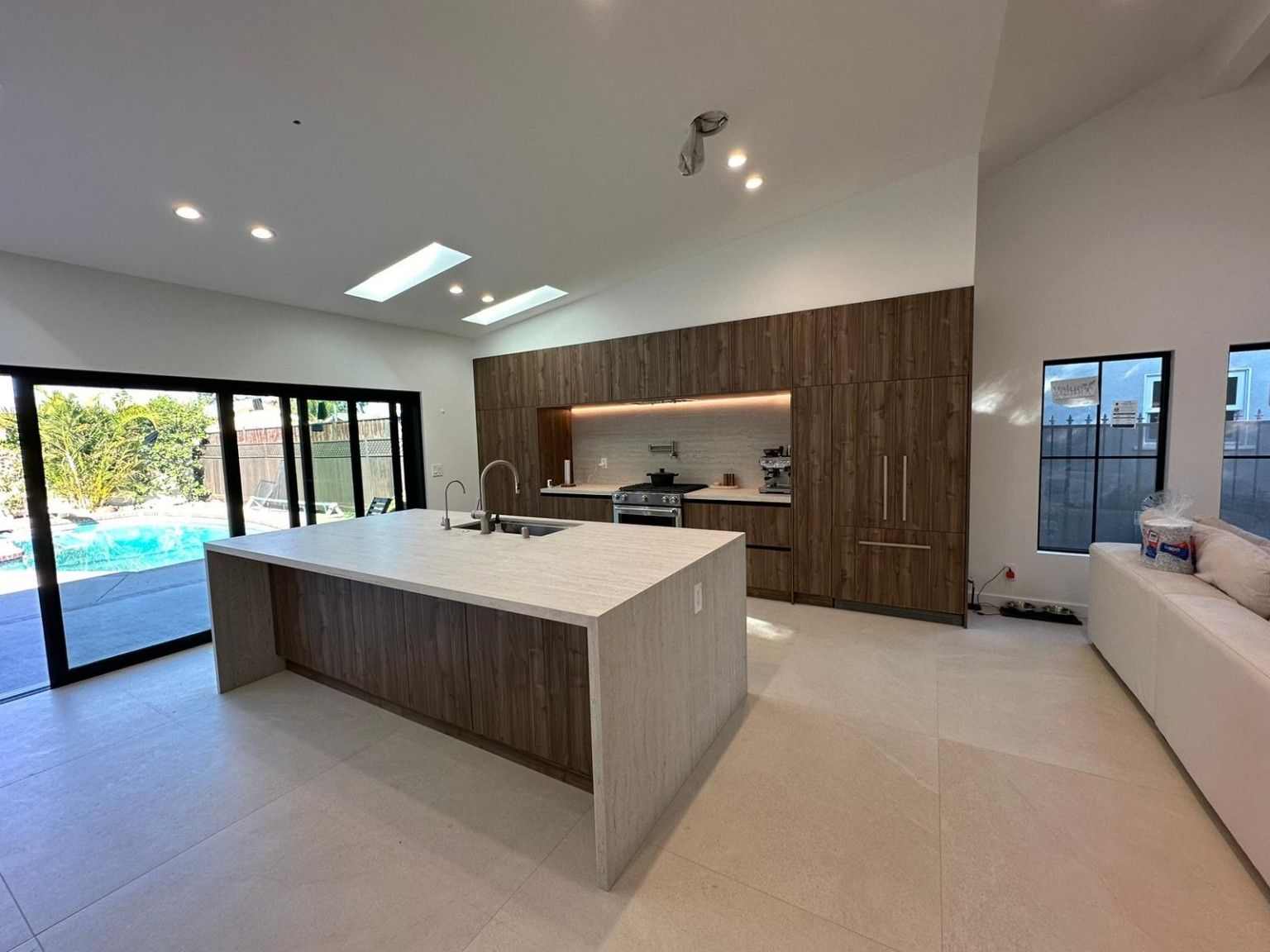 Kitchen project with a large island, wood cabinetry, skylights and sliding doors opening toward the yard