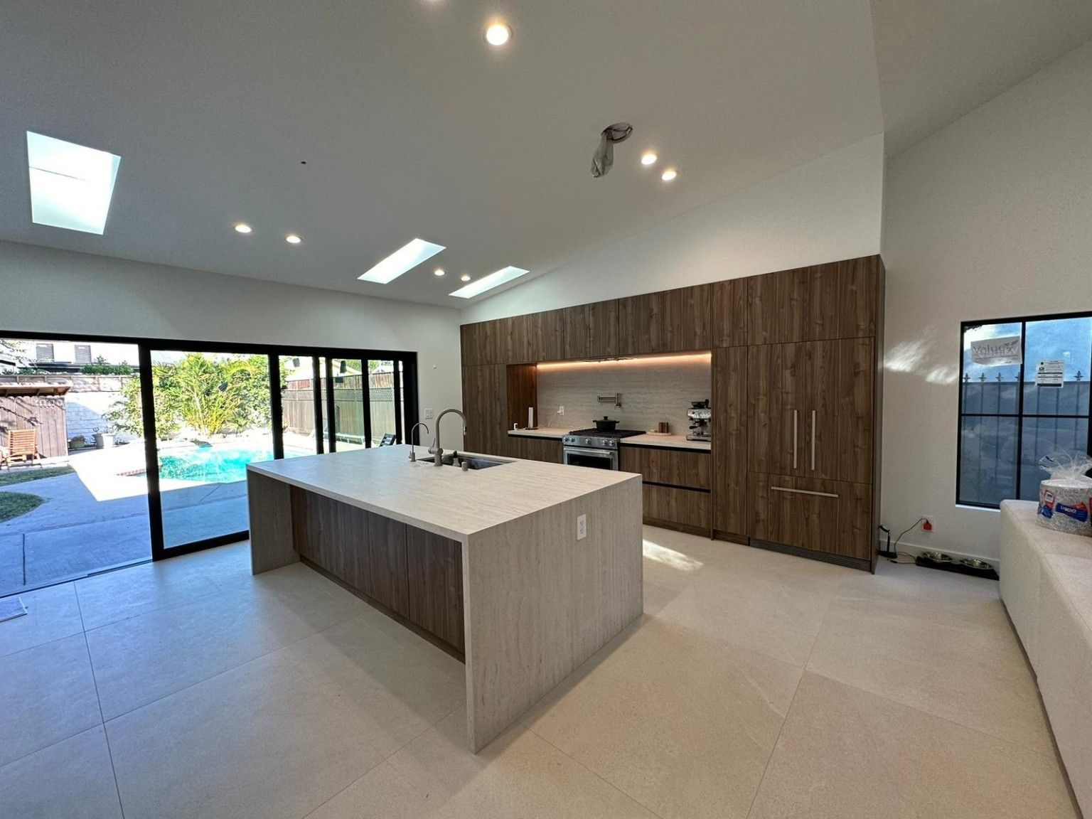 Wood kitchen island beneath skylights with large sliding doors open to the yard