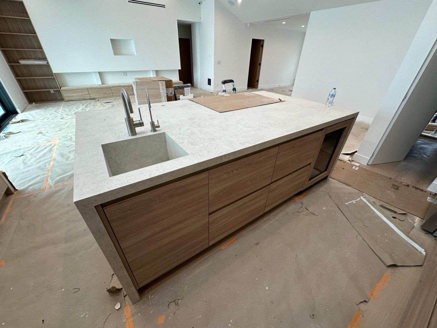 Wood kitchen island with a sink and countertop during installation, with protective materials nearby