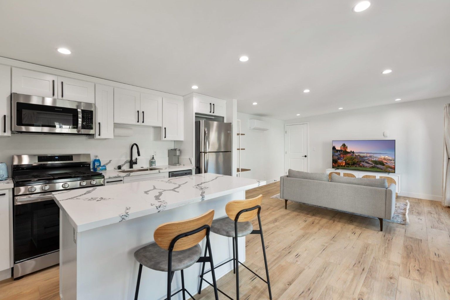 White kitchen island with two stools beside an open sitting area