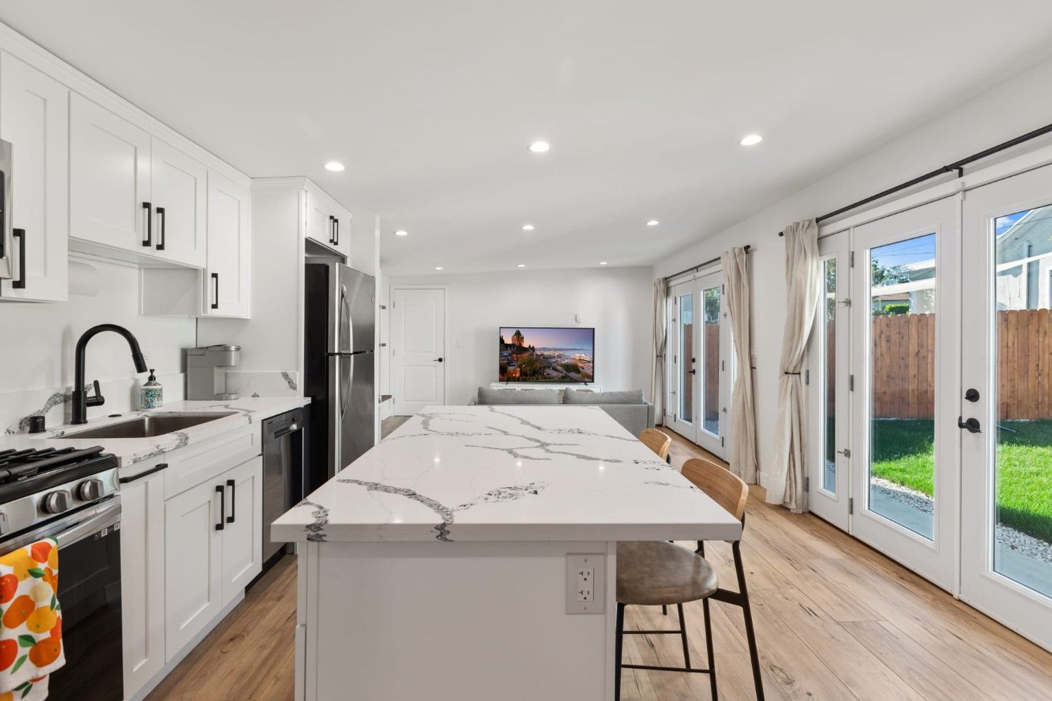 View from a white kitchen island toward a sitting area and glass doors