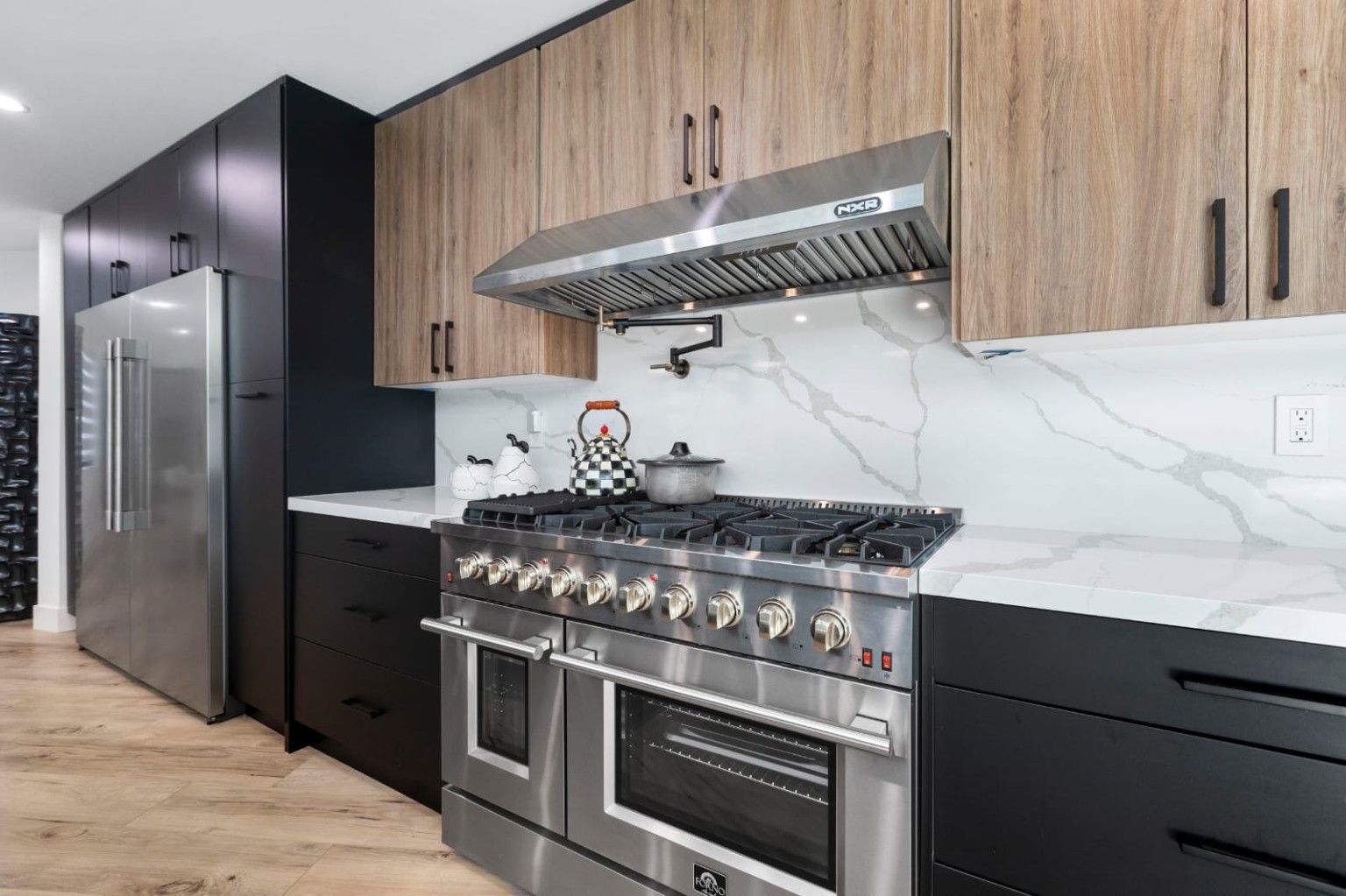 Stainless range and hood between wood upper cabinets and dark base cabinets