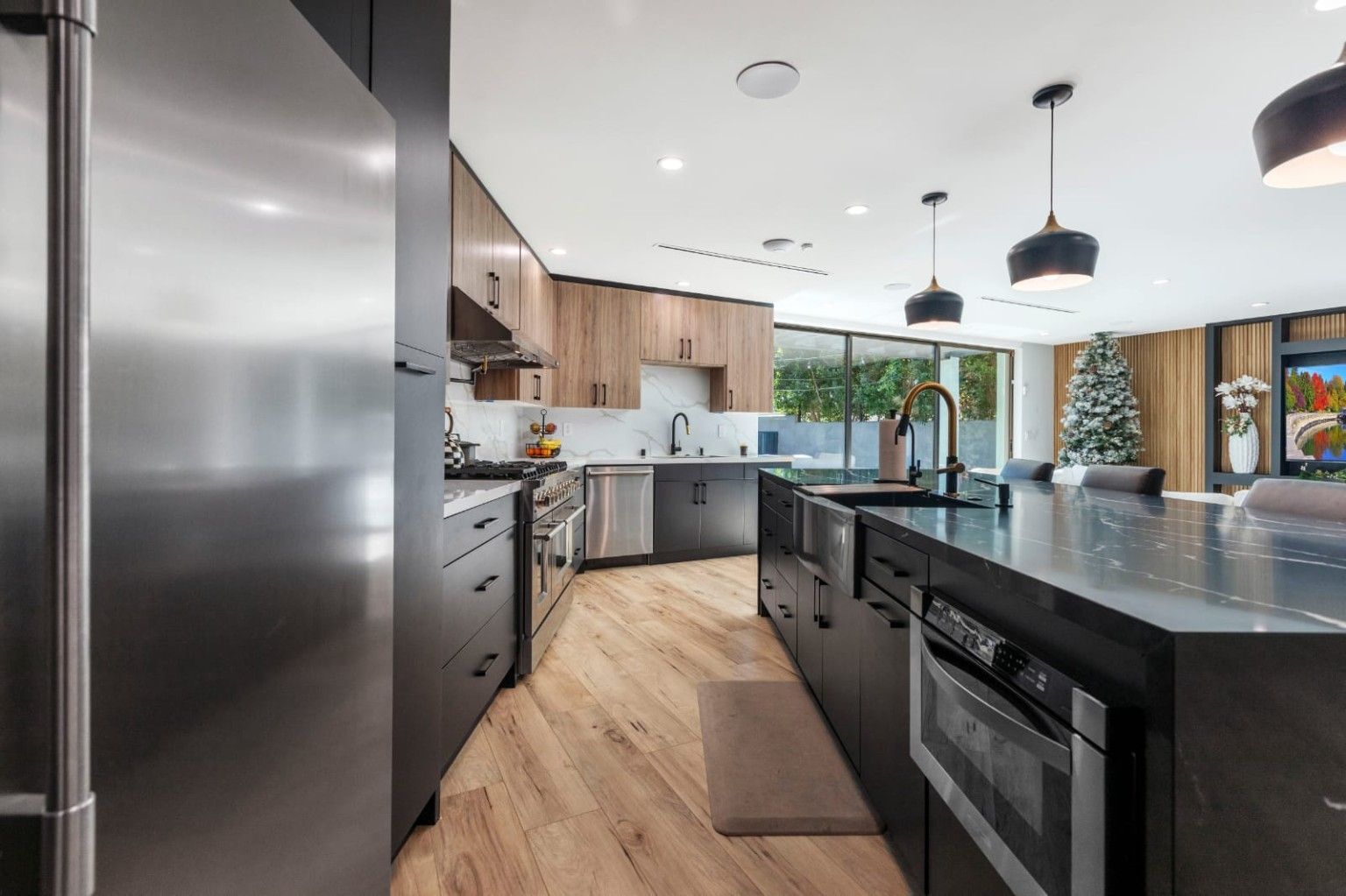 Kitchen with wood upper cabinets, dark base cabinets and pendant lights over an island