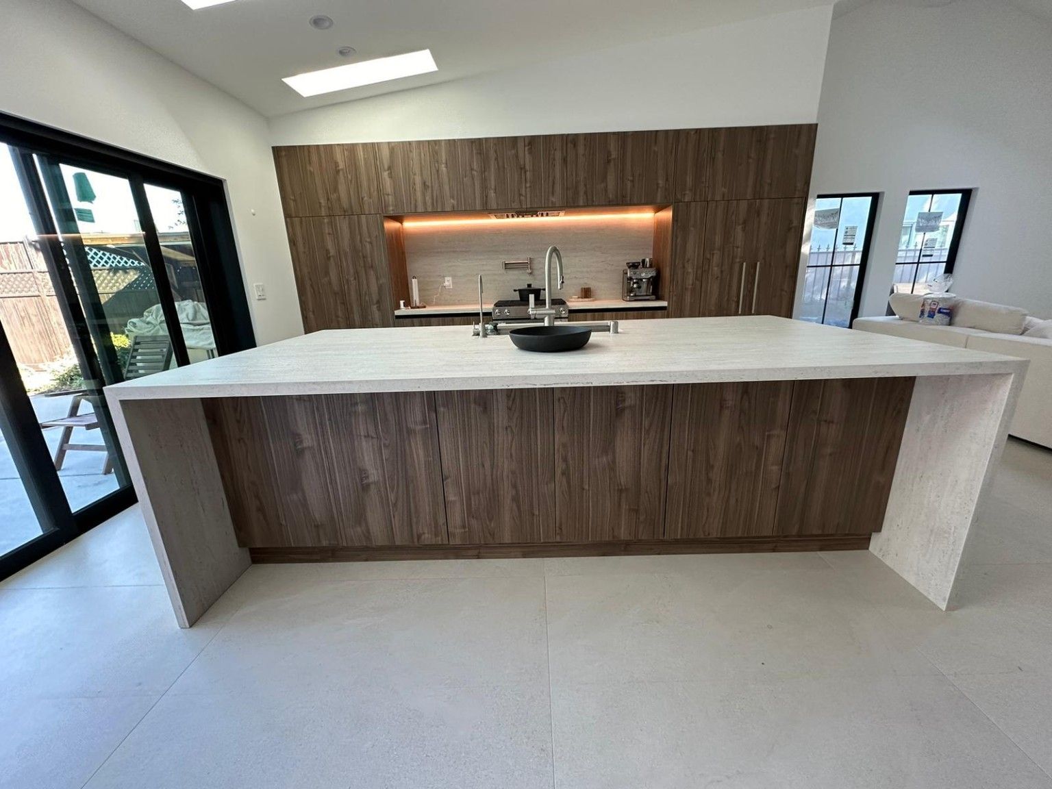 Front view of a wood kitchen island with a light waterfall countertop