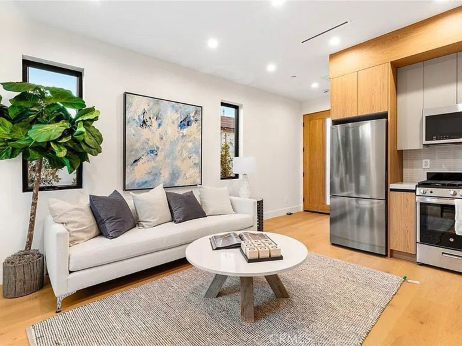 Living room with a white sofa and wood flooring beside an open kitchen