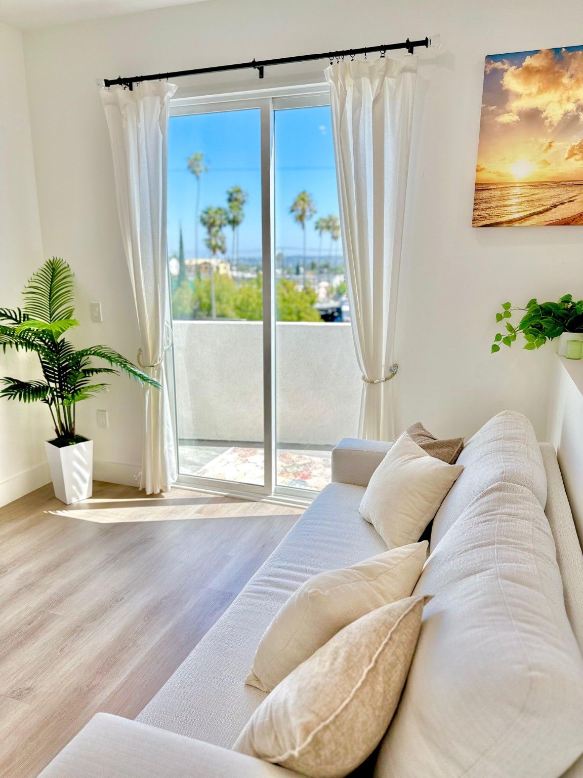 Living space with a light sofa, wood-look flooring and a glass door