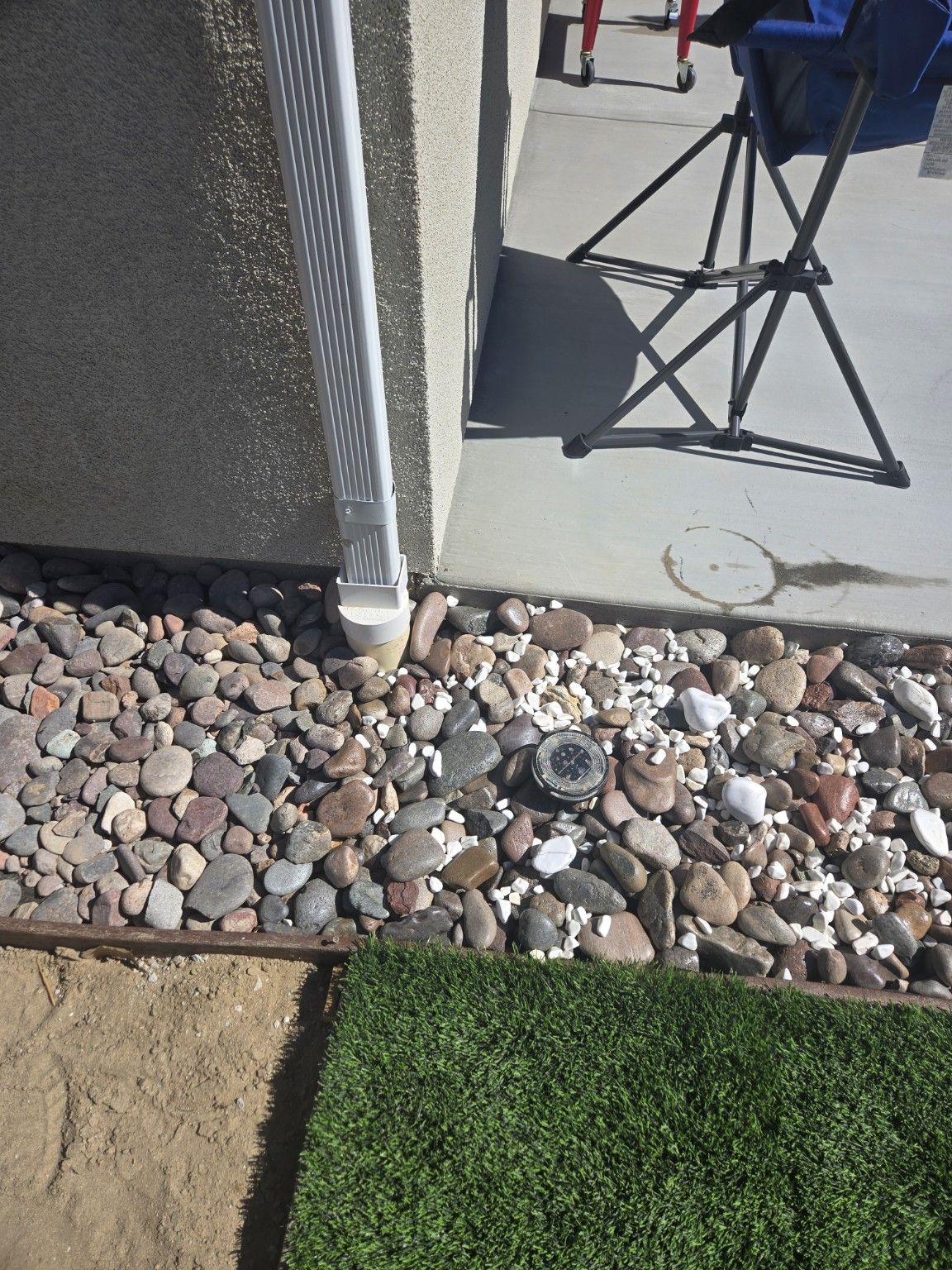 Decorative stones and a small ground light beside a concrete path and turf