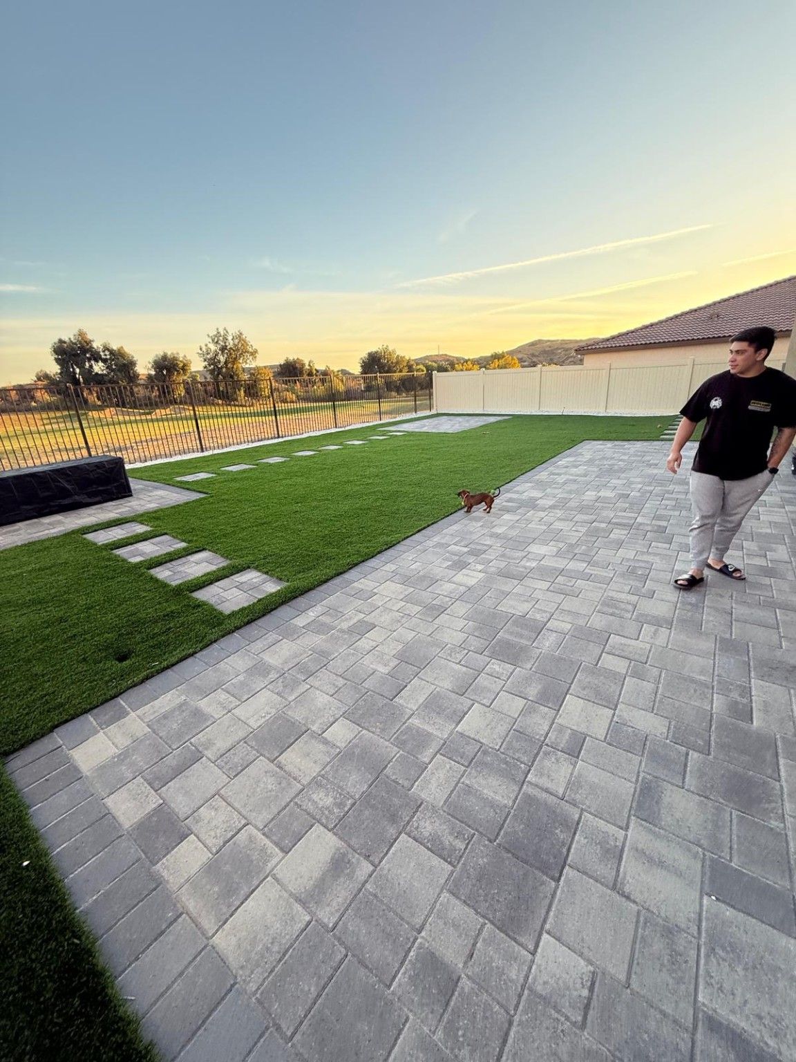 Paver patio beside artificial turf and a stepping-stone path