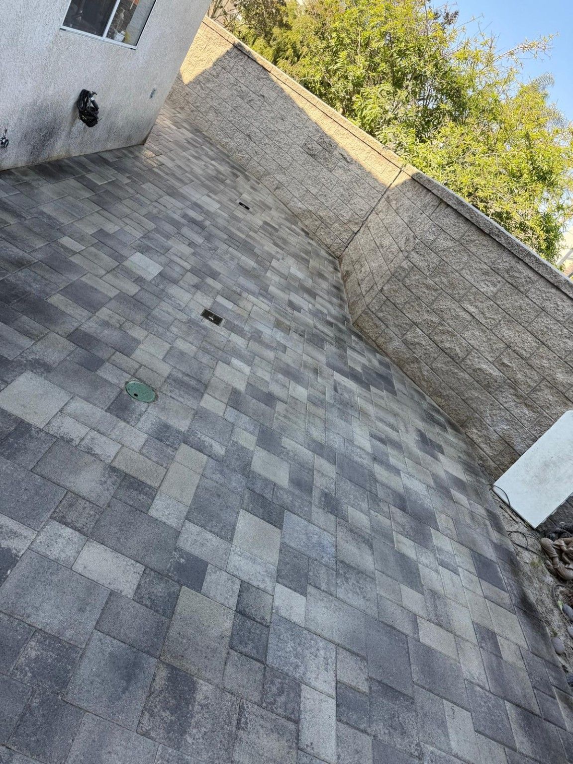Gray paver walkway beside the house and a boundary wall