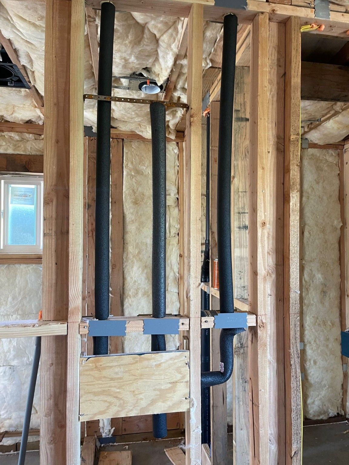 Vertical plumbing and connections within an insulated framed wall